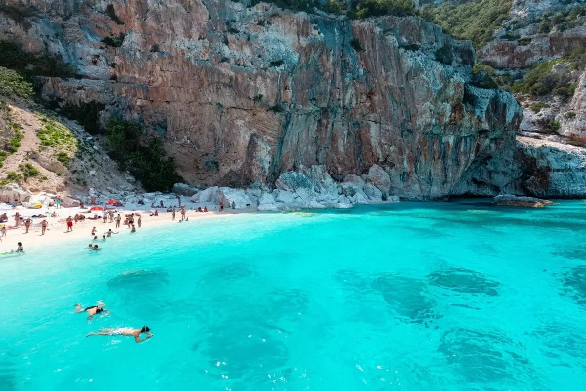 Una spiaggia con acqua cristallina e scogliera sullo sfondo, situata a Cala Gonone.