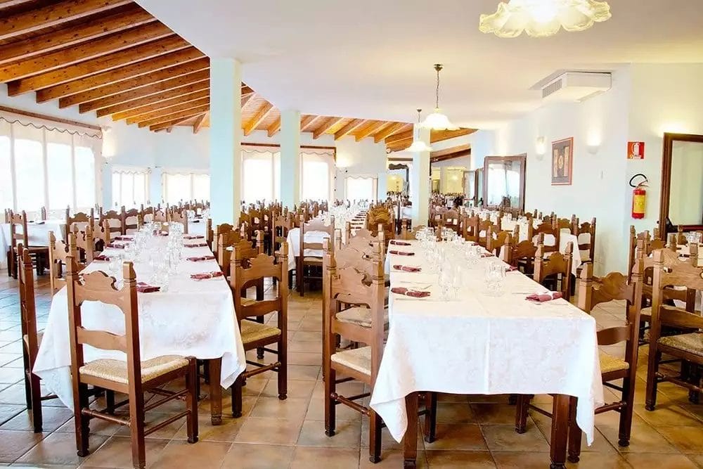 Il Club Esse Cala Gonone Beach Village dispone di un'ampia sala da pranzo arredata con bellissimi tavoli e sedie in legno.