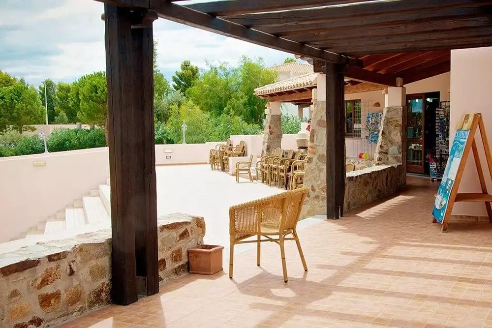 Un patio con sedie e tavolo davanti alla casa del Beach Village Club Esse a Cala Gonone.