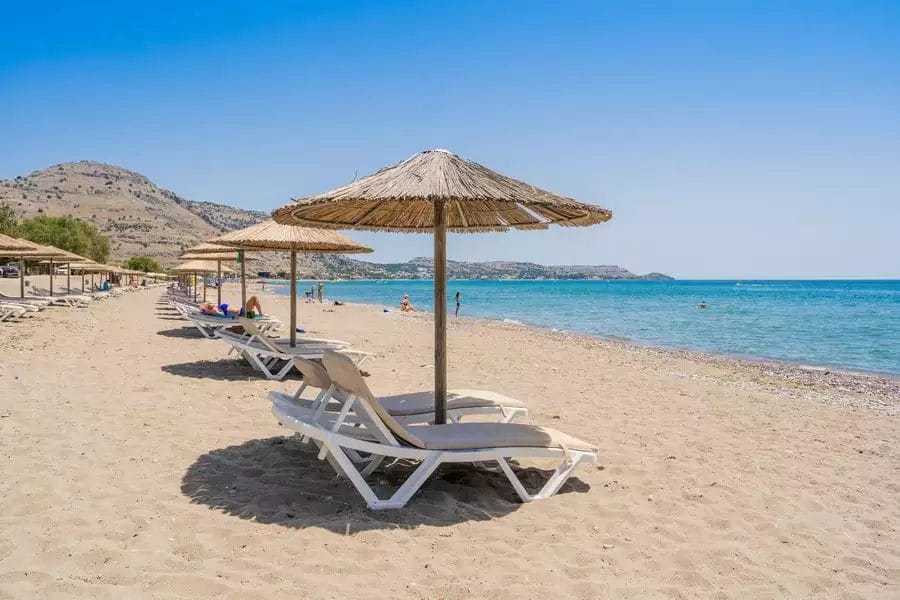 Lardos Bay, una spiaggia sabbiosa con sedie a sdraio e ombrelloni.