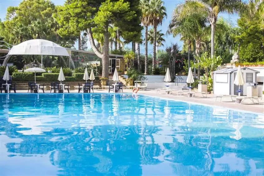 Una piscina con lettini e ombrelloni a Fontane Bianche, del Nicolaus Club.