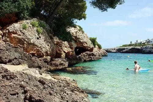 Un gruppo di persone nuota nell'acqua vicino a una costa rocciosa al BLAU PUNTA REINA RESORT.