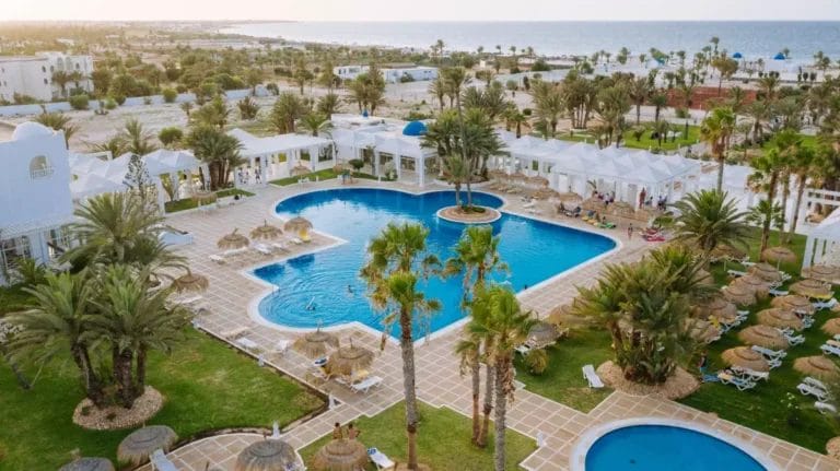 Una veduta aerea del Djerba Golf Resort, con una piscina circondata da palme.