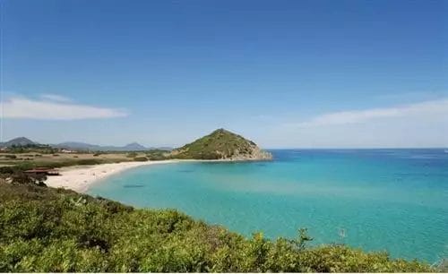 Una spiaggia con acqua cristallina e una collina sullo sfondo, situata nei pressi dell'ALMA RESORT.