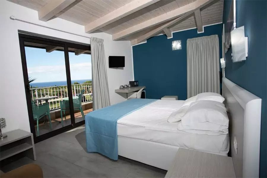 Una camera con letto e balcone vista oceano presso un resort Alpiclub sulla Costa degli Dei.