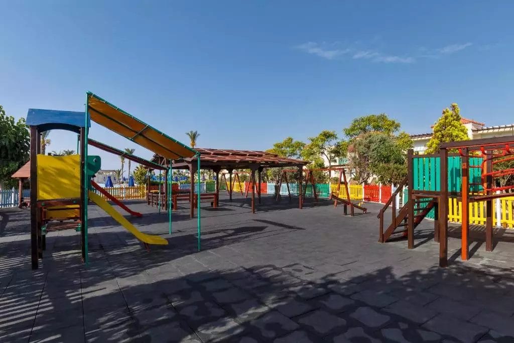 Un parco giochi per bambini con scivoli e altalene colorati, situato all'interno del resort LINDOS PRINCESS.