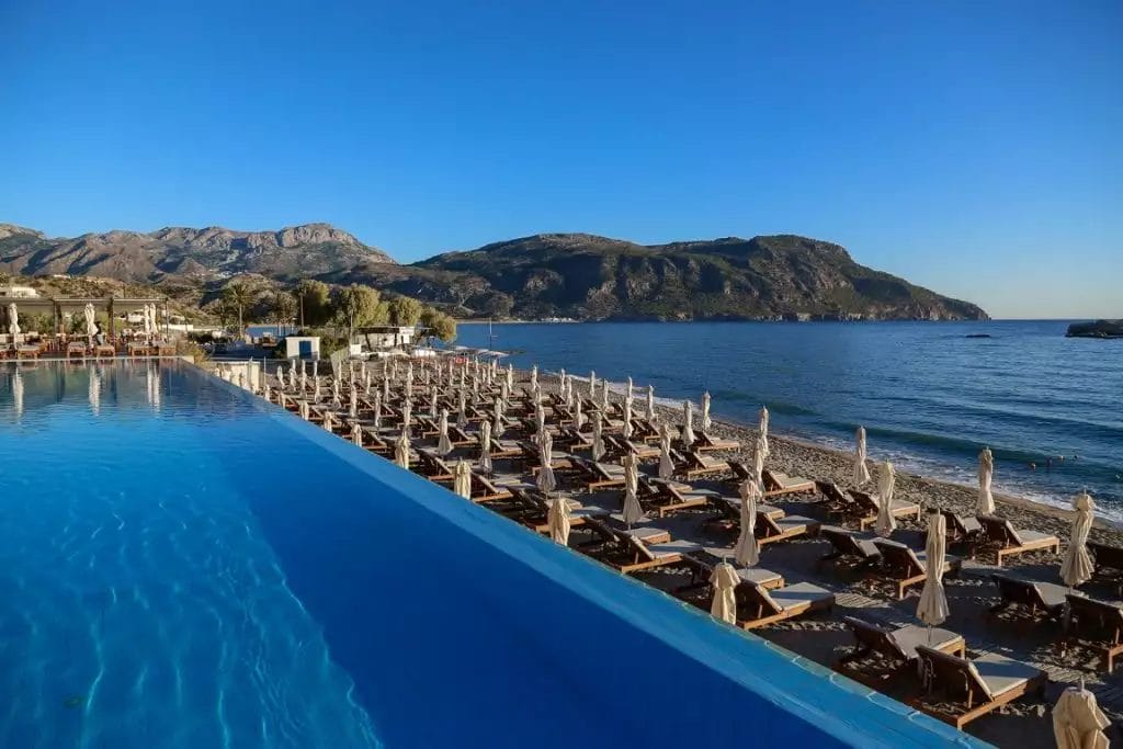 Una piscina con lettini e montagne sullo sfondo.