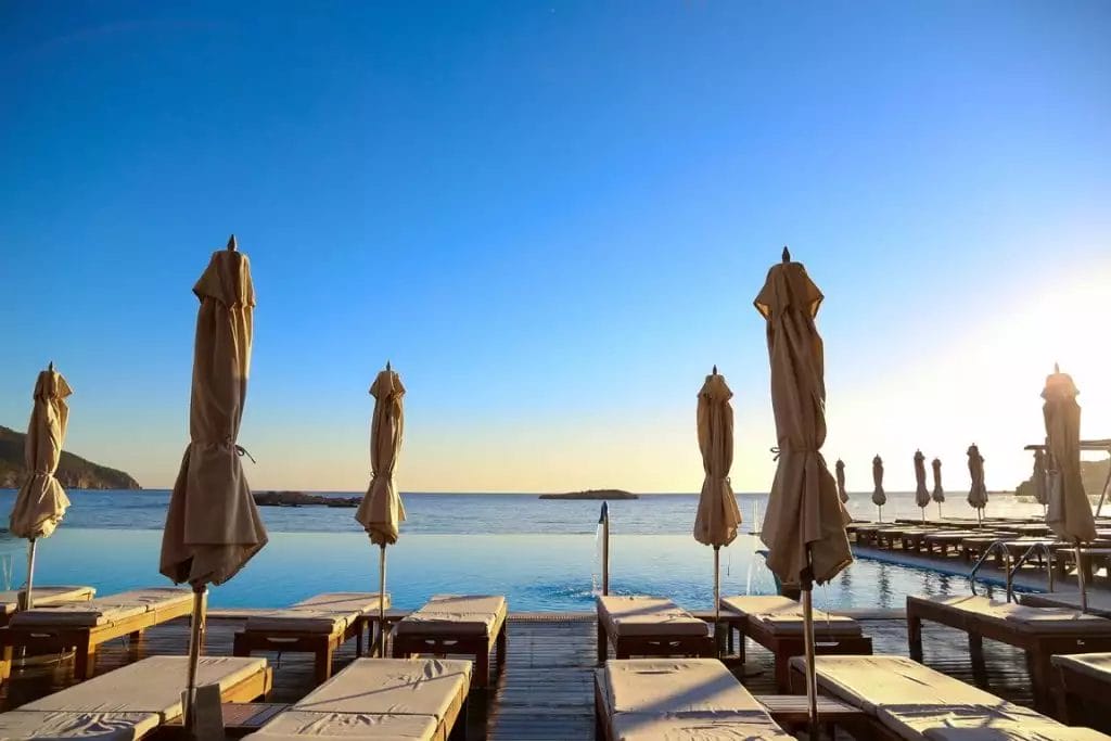 Una piscina con lettini e ombrelloni al tramonto in riva al mare.