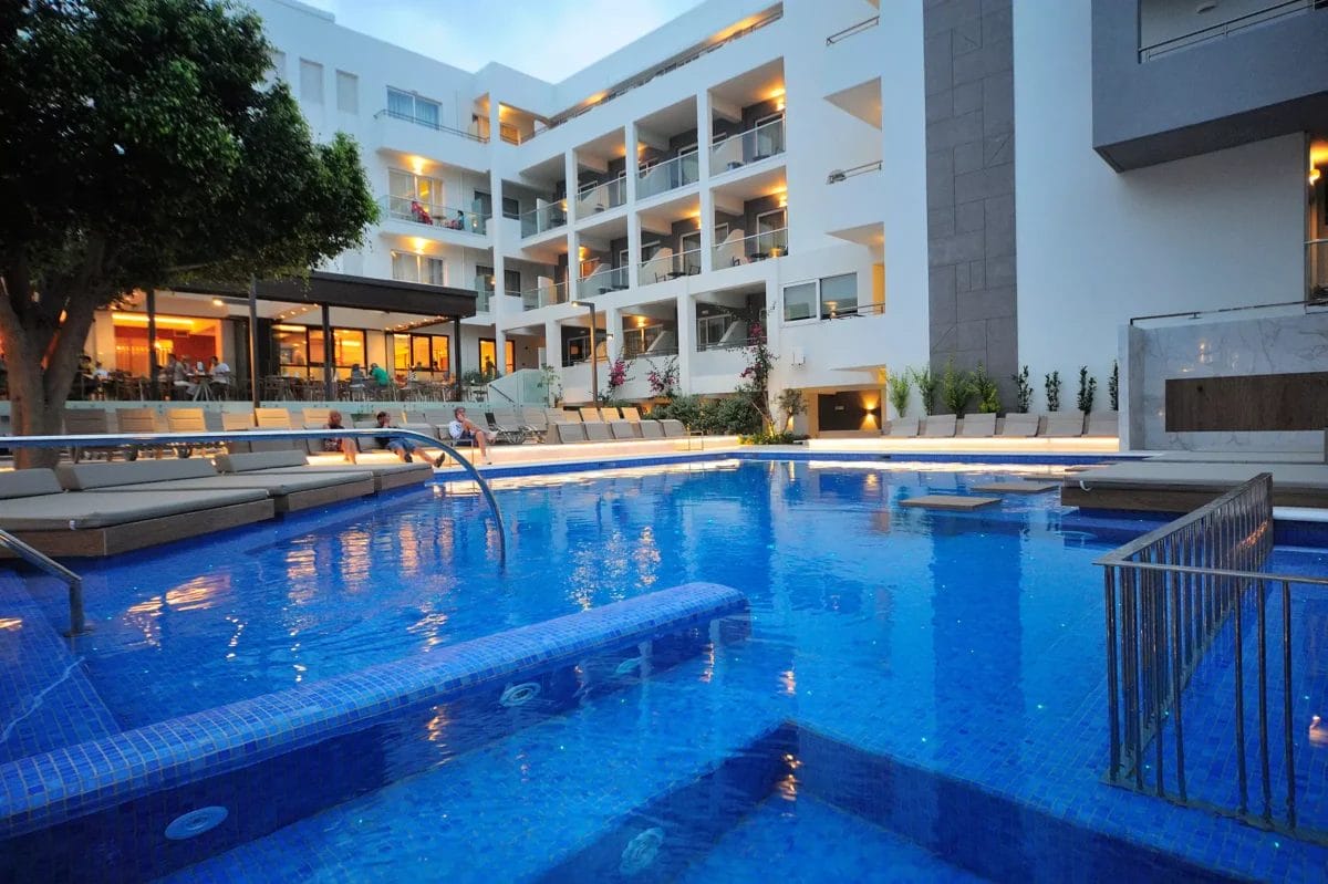 La piscina dell'hotel ALPISELECT emana un'AMBIENTE accattivante mentre il sole tramonta, proiettando una luce soffusa sul tranquillo ATRIO.