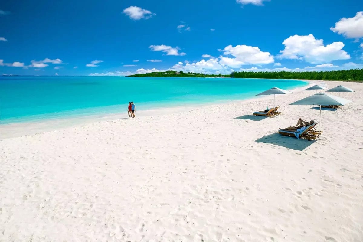 Una spiaggia di sabbia bianca con lettini e ombrelloni, situata presso la spiaggia Viva Fortuna.