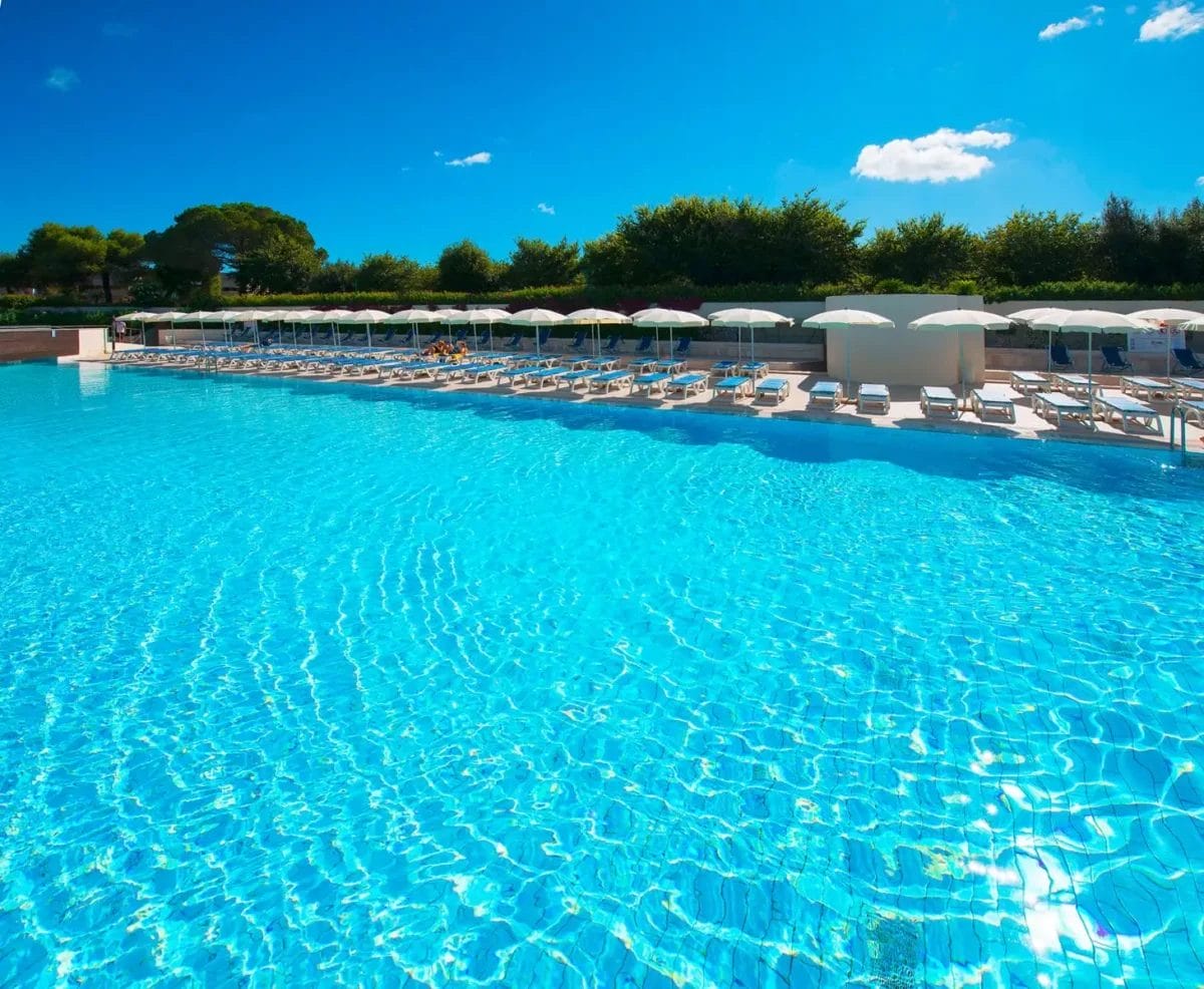 Una piscina BRAVO con lettini e ombrelloni presso ALIMINI.