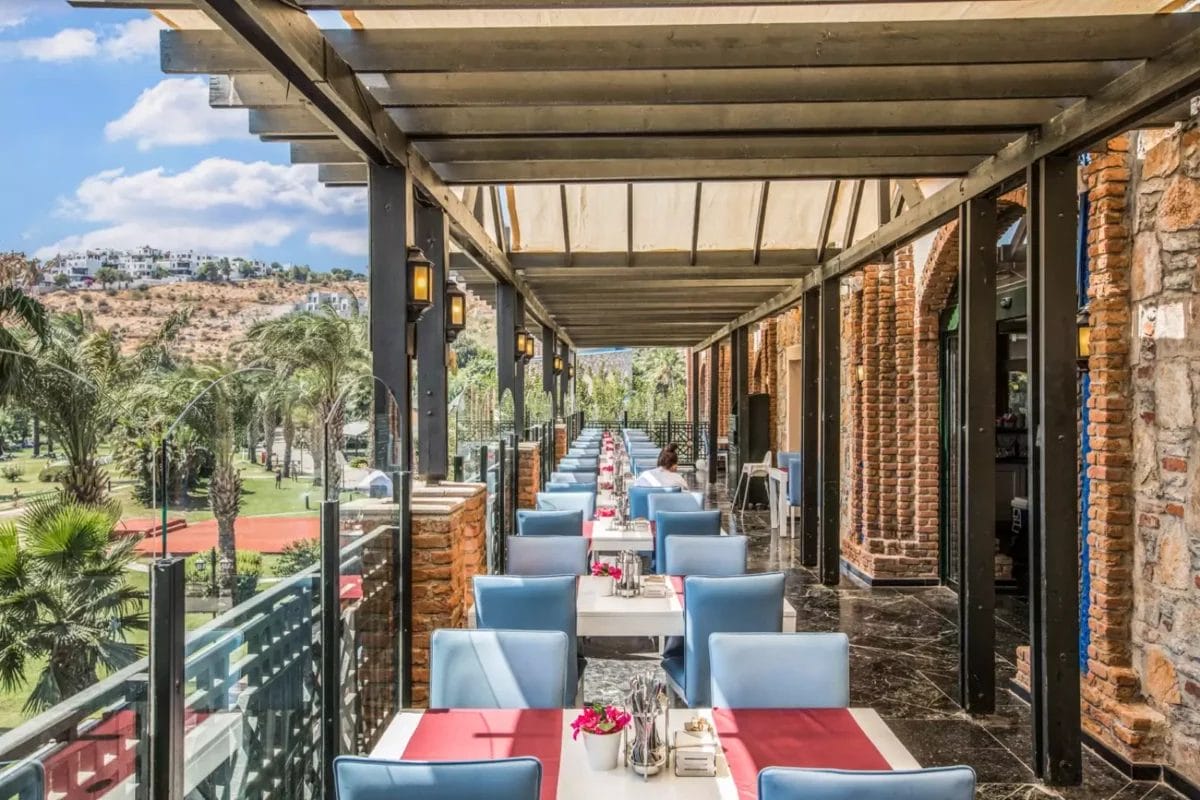 Un ristorante imperiale con tavoli e sedie su un balcone che si affaccia su un campo da golf.