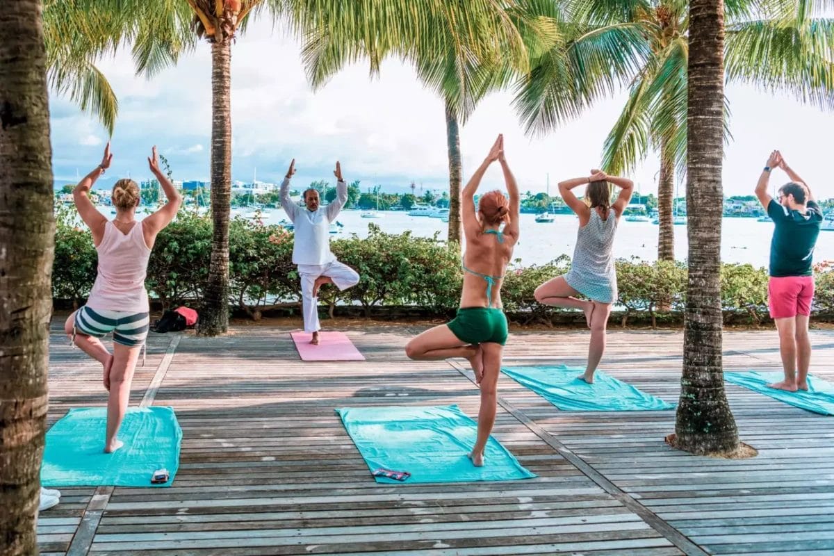 Un gruppo di persone che fa yoga su una terrazza con palme al Bravo Premium.