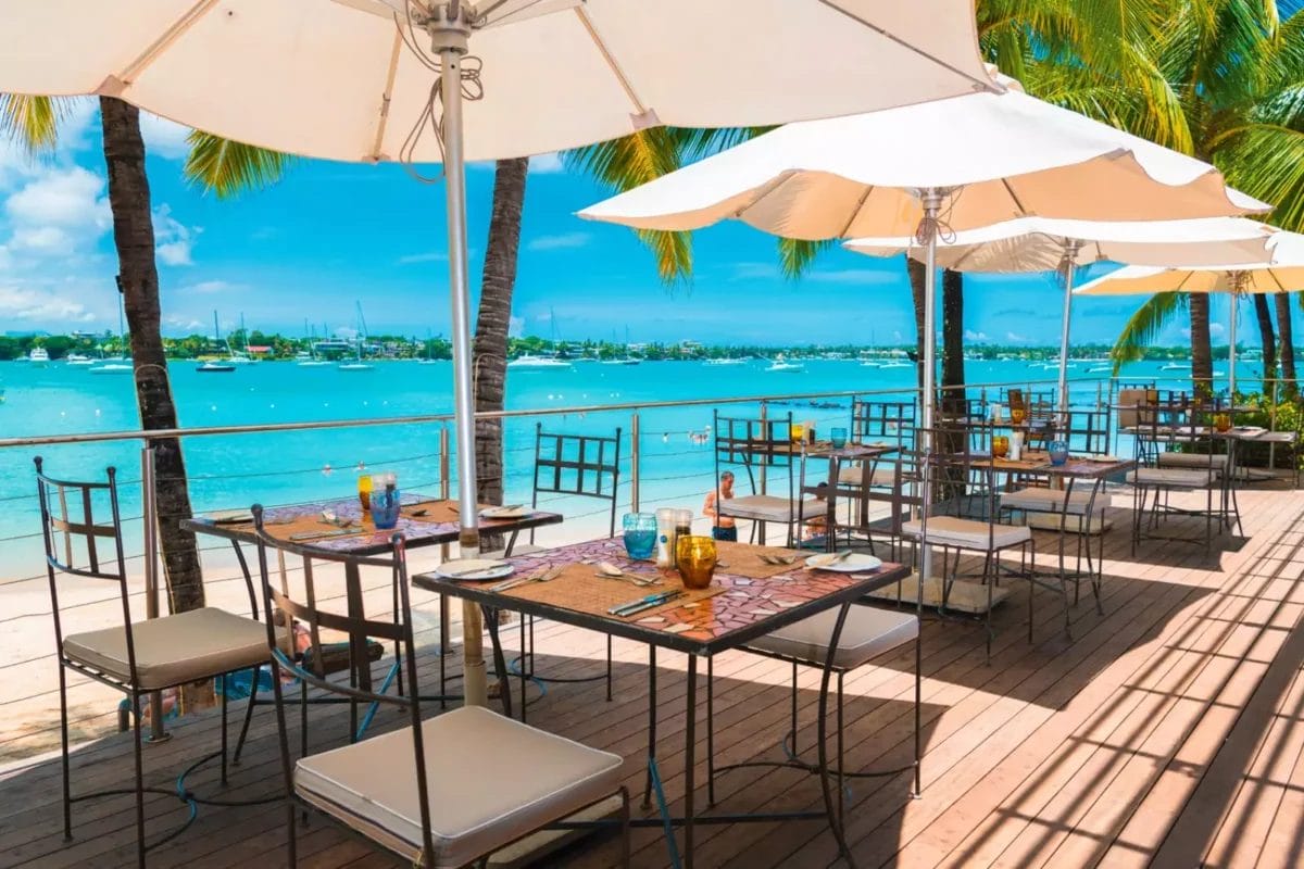 Un ristorante PREMIUM con tavoli e ombrelloni su una terrazza con vista sull'oceano.