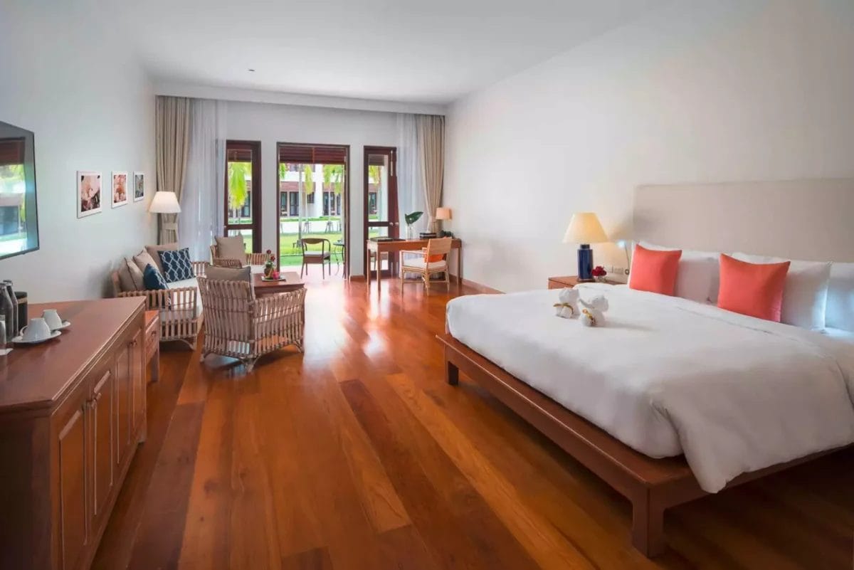 Una camera premium nell'hotel Bravo a Khao Lak, dotata di un ampio letto ed eleganti pavimenti in legno.