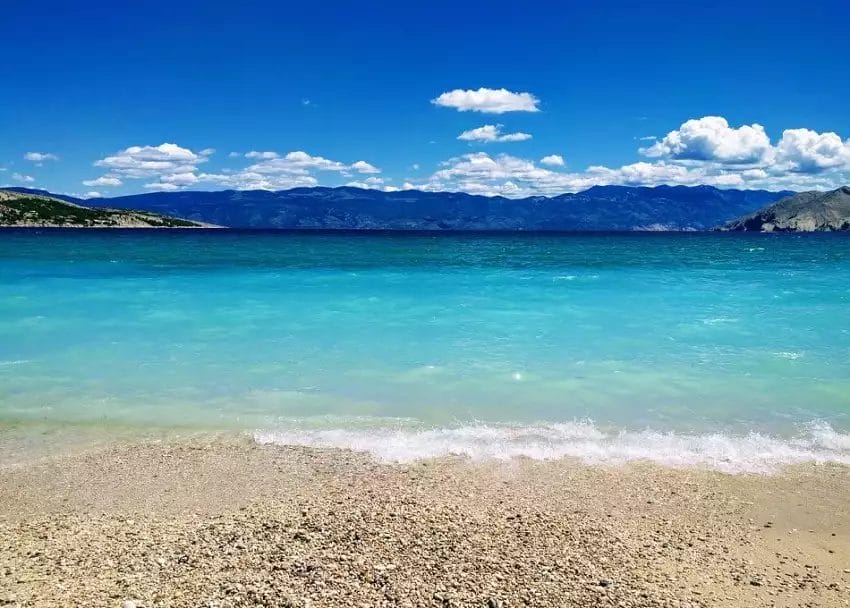 Una splendida spiaggia con acque cristalline e maestose montagne sullo sfondo.