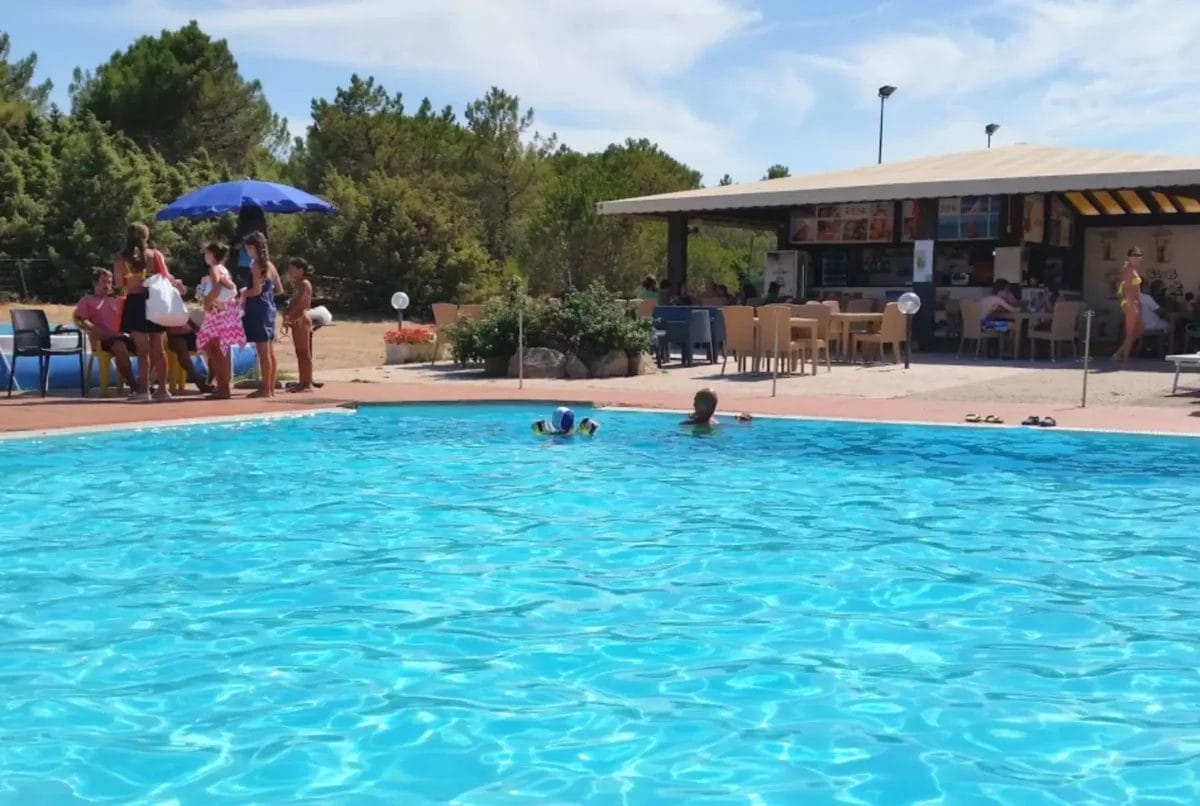 Un locale gallurese con gente seduta attorno ad una piscina.