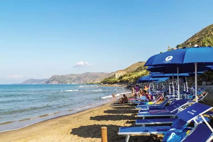 Una spiaggia con sedie e ombrelloni del FUTURA CLUB CILENTO allineati sulla sabbia.