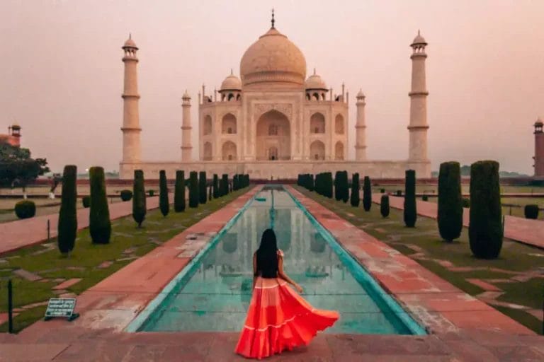 Una donna accomodante con un vestito arancione che si gode un tour del Taj Mahal in India.