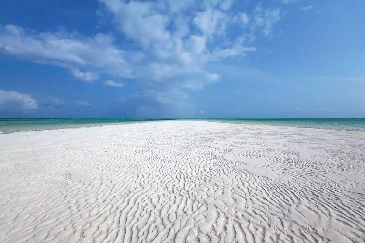 Una spiaggia di sabbia bianca con un cielo azzurro sullo sfondo.