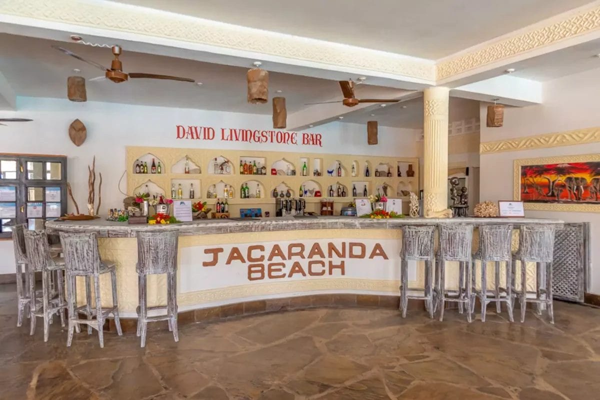 Un bar con sgabelli e un cartello che dice Jacaranda Beach Resort.