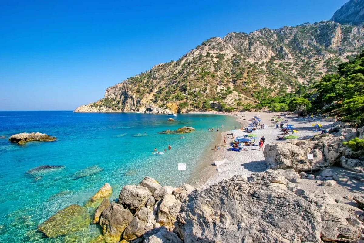 Una spiaggia con scogliere rocciose e acqua blu cristallina.