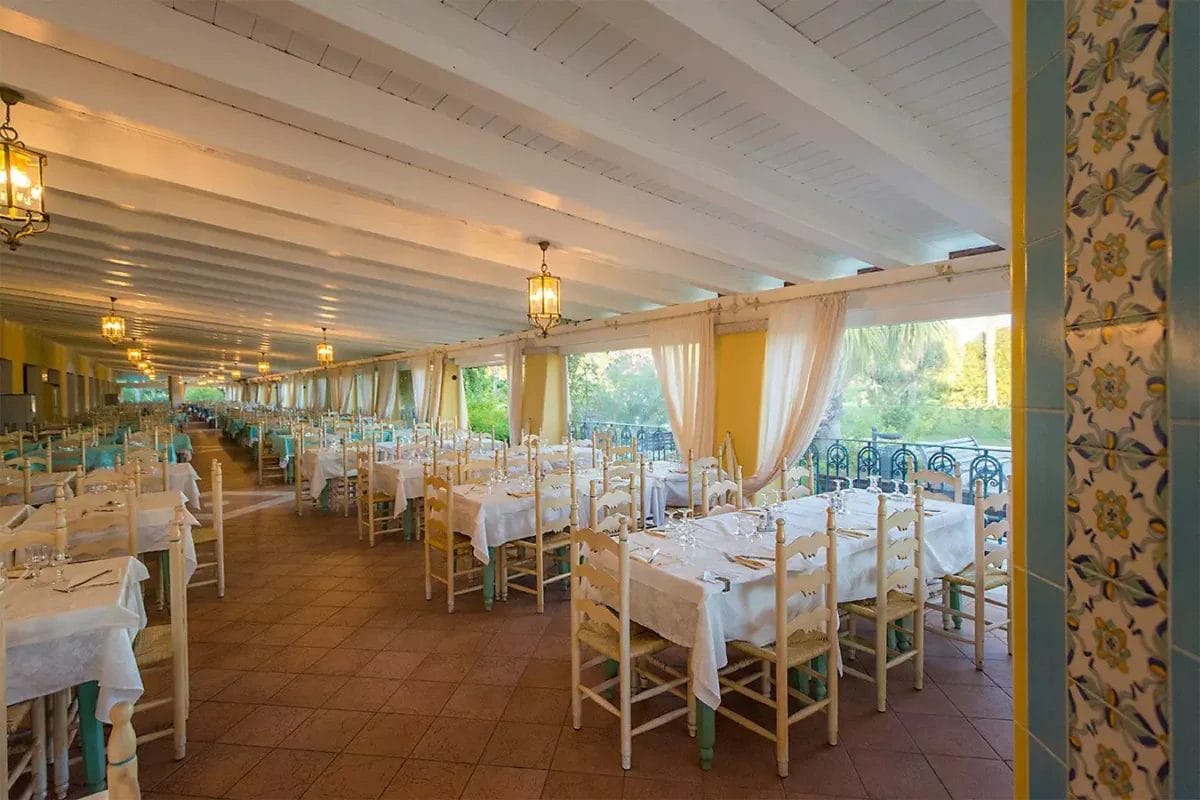 Un'ampia sala da pranzo con tavoli e sedie, situata presso il MARINA RESORT.