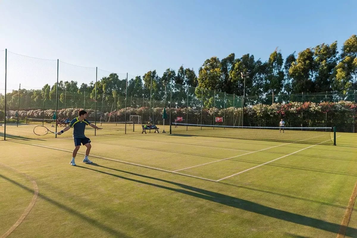 Un uomo sta giocando a tennis sul campo del MARINA RESORT.