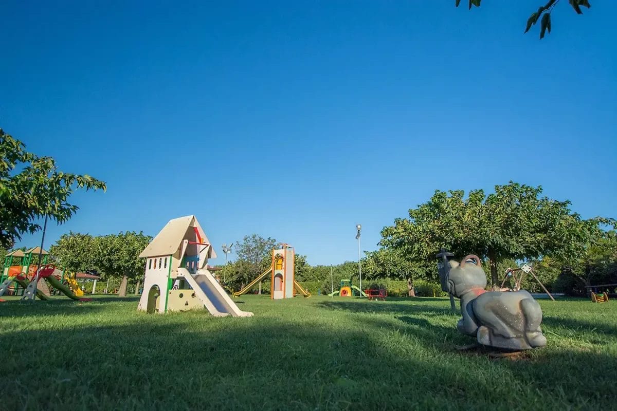 Area giochi per bambini con giocattoli e scivolo presso uno stabilimento balneare.