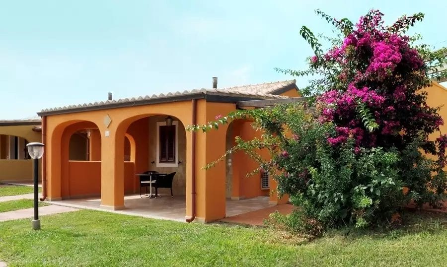 Un resort sulla spiaggia con un porto turistico e una casa arancione con fiori in giardino.