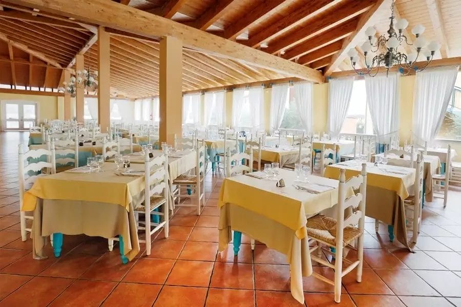 Una spaziosa sala da pranzo con tavoli e sedie, situata all'interno di uno stabilimento balneare a Marina Rey.