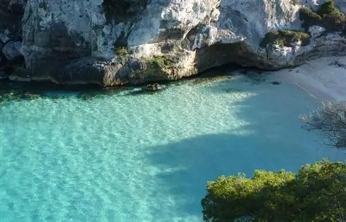 Una veduta aerea di Bravo Minorca, una spiaggia con acqua limpida e scogliere.