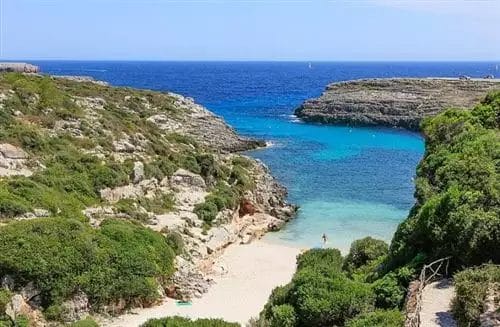 Una spiaggia sabbiosa vicino ad una scogliera rocciosa a Bravo Menorca.