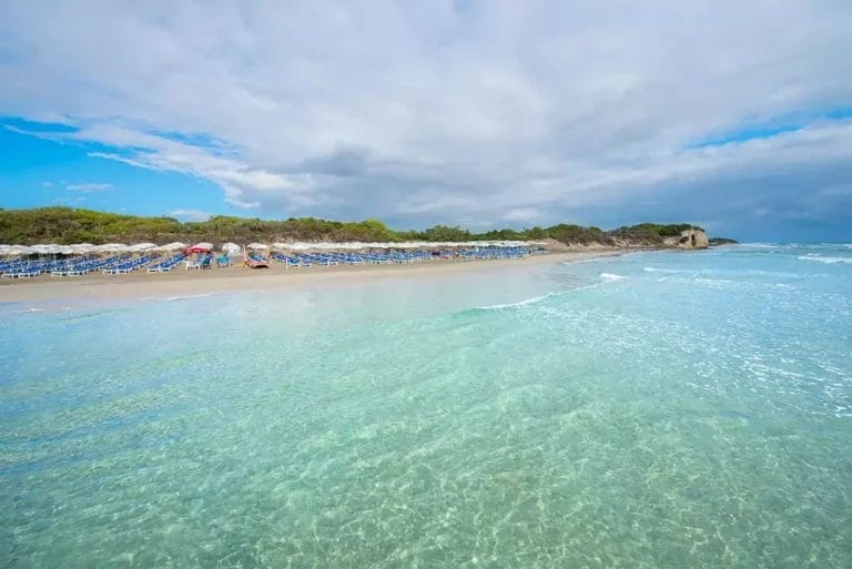 Una spiaggia con acqua limpida, ombrelloni blu e BRAVO.