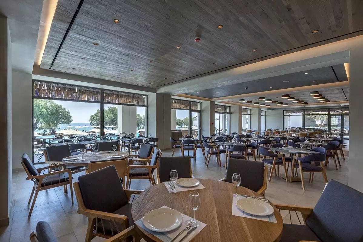 Un ristorante VERACLUB con tavoli e sedie in legno e vista sull'oceano.