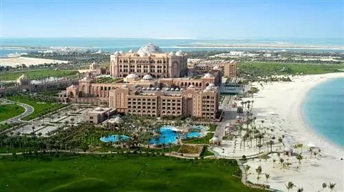 Lussuoso resort Royal M Hotel fronte mare con ampie piscine e vegetazione lussureggiante, affacciato su un tranquillo tratto di spiaggia sabbiosa ad Abu Dhabi.