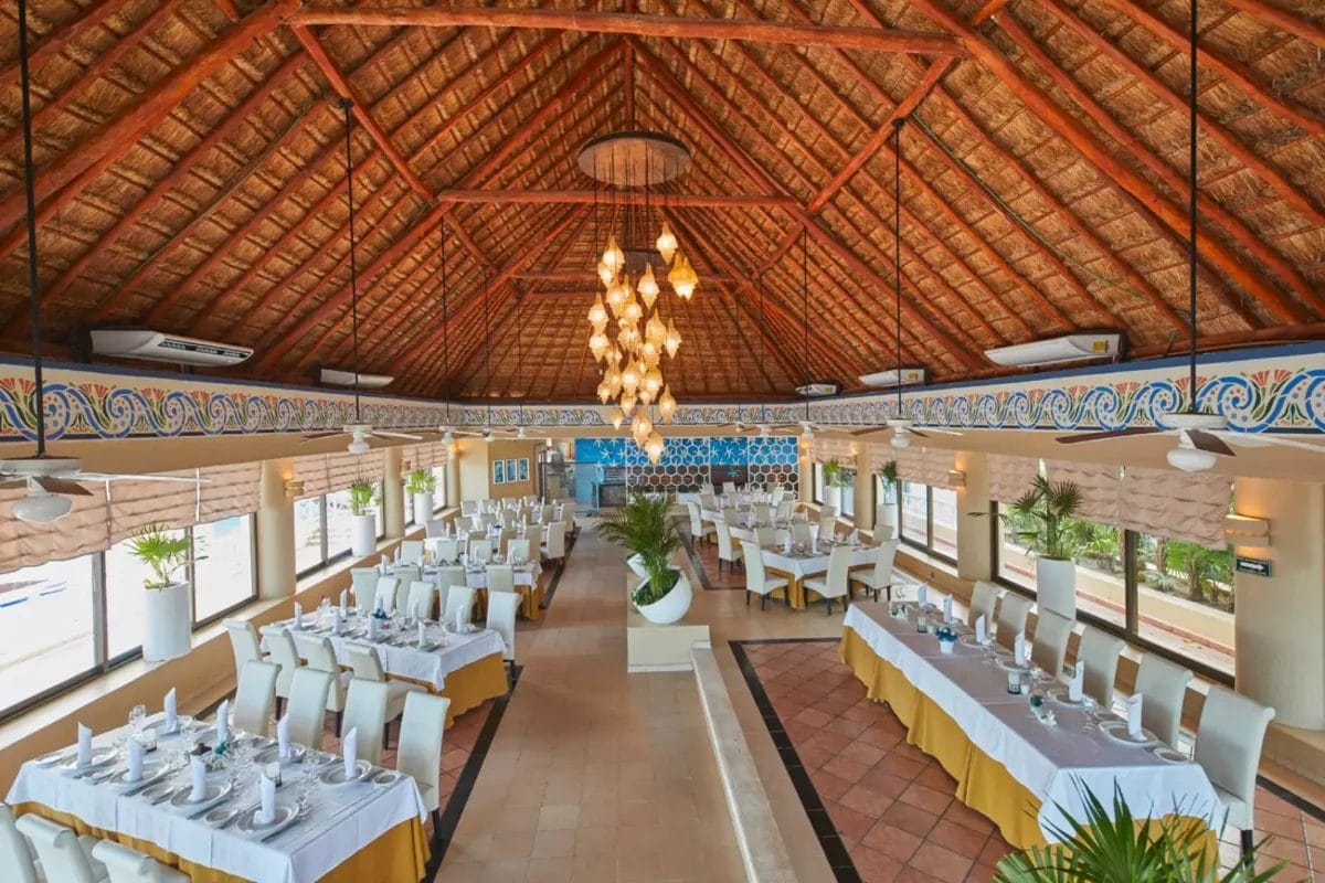 Una lussuosa sala da pranzo al Bahia Principe con tavoli e sedie bianchi.