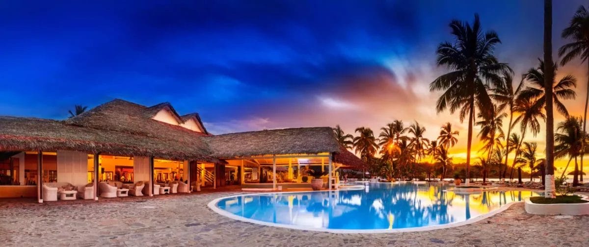 Vista panoramica del resort Bravo Andilana Beach in Madagascar con piscina al tramonto.