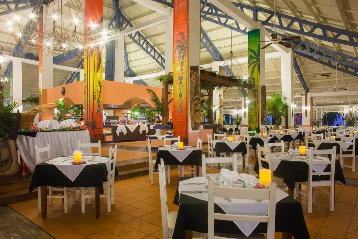 Gli interni spaziosi e luminosi del ristorante con decorazioni tropicali, tavoli apparecchiati e colonne colorate al BRAVO ANDILANA BEACH Resort.