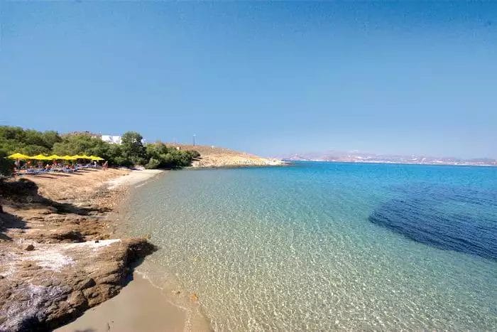 Una spiaggia con ombrelloni Bravo e una costa rocciosa.