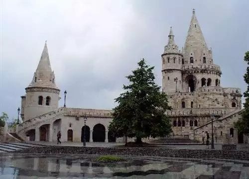 Torri e guglie neogotiche del Bastione dei Pescatori sotto un cielo nuvoloso a Budapest.