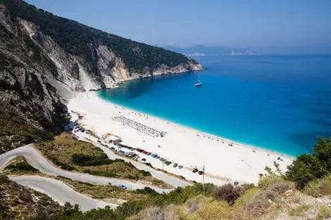 Una strada tortuosa che conduce a una famosa spiaggia con sabbia bianca, ombrelloni e un mare cristallino presso l'Alpislect Apostolata Island Resort.