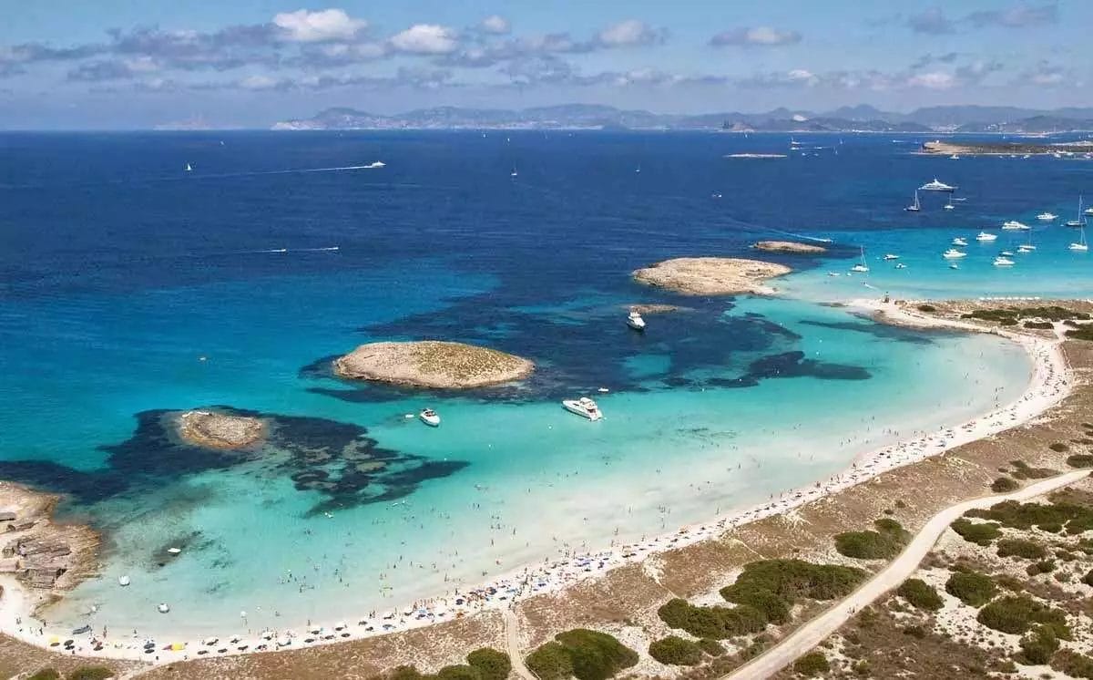 Una veduta aerea della spiaggia di Formentera con barche e acqua blu.