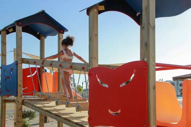 Una bambina è in piedi su una struttura di gioco in legno in un resort.