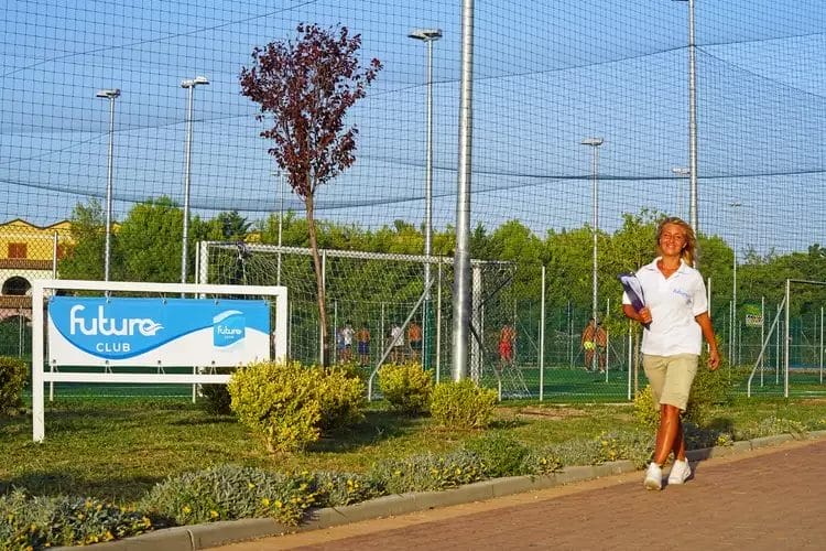 Una donna che cammina lungo un sentiero vicino a un campo da tennis al Danaide Resort.