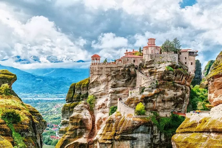 Un viaggio in Grecia rivela un monastero storico adagiato sopra una formazione rocciosa imponente, circondato da una vegetazione rigogli