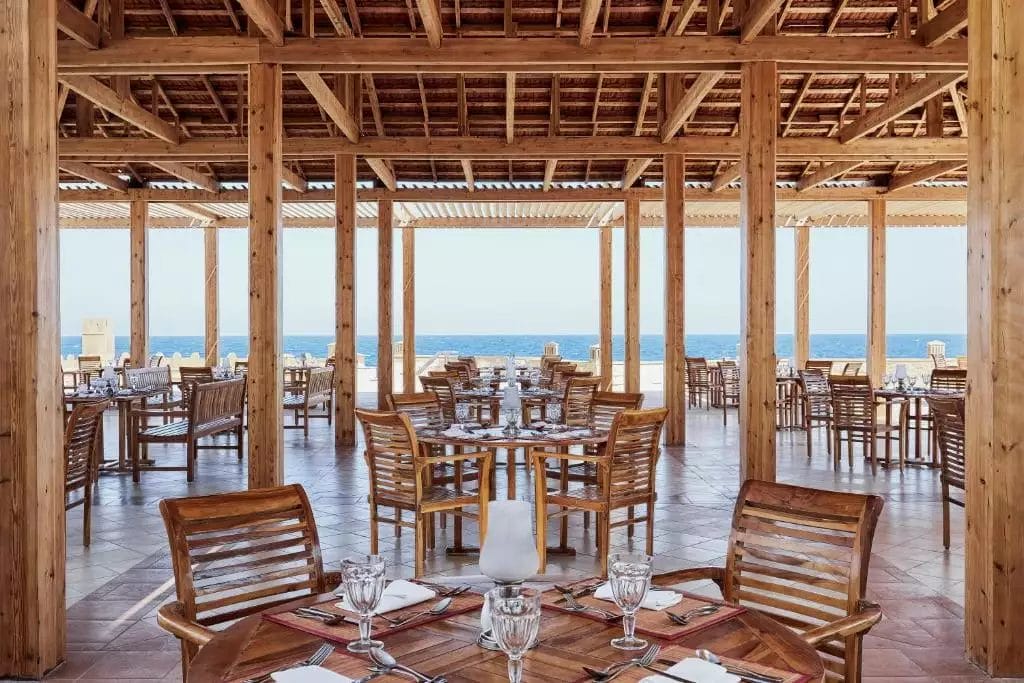 Cena in riva al mare in un elegante ristorante in legno sulla spiaggia con una vista serena sull'oceano al JAZ GRAND MARSA.