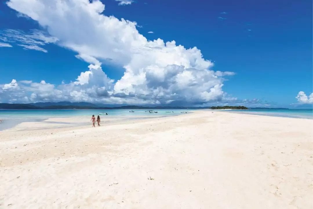SPIAGGIA sabbiosa di BRAVO ANDILANA con cielo limpido e gente che cammina in lontananza.