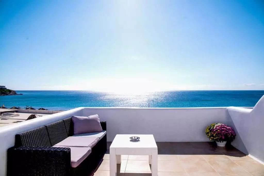 Balcone sul mare del resort con mobili da esterno che si affaccia su un oceano blu brillante.