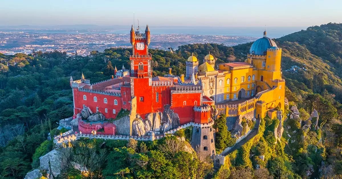 Un castello si trova in cima a una scogliera che domina una città del Portogallo.